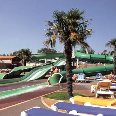 Toboggan aquatique vert et chaises longues bleues au Camping Le Curtys