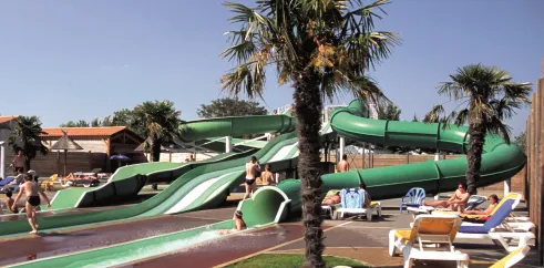 Toboggan aquatique vert et chaises longues bleues au Camping Le Curtys