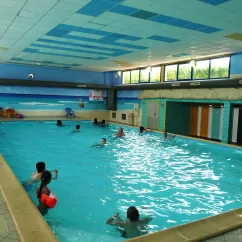Piscine intérieure du Camping Le Curtys avec enfants nageant.