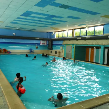Piscine intérieure du Camping Le Curtys avec enfants nageant.