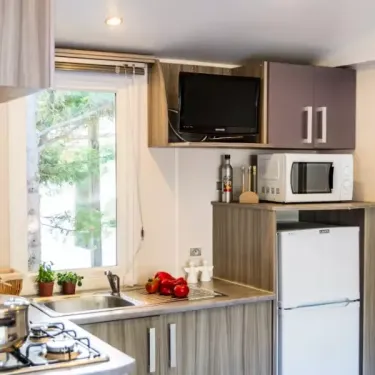 Mobil Home Confort Clim 2 Chambre TV - 4 Pers. - Camping La Croix du sud : cuisine avec TV et réfrigérateur