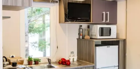 Mobil Home Confort Clim 2 Chambre TV - 4 Pers. - Camping La Croix du sud : cuisine avec TV et réfrigérateur