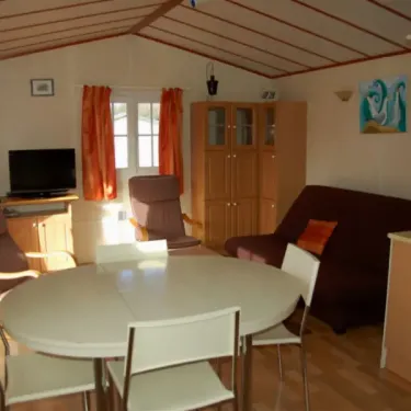 Mobil Home Goeland 3CH - 6P - Camping Les Hauts de Port Blanc, salle à manger avec table ronde et canapé.