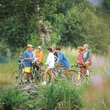 Groupe de personnes à vélo au Camping Les Sables de Cordouan, en forêt.