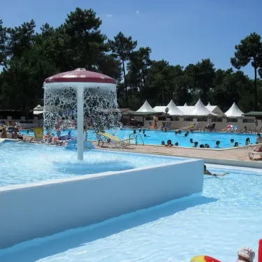 Piscine extérieure avec fontaine et tentes blanches au Camping Les Sables de Cordouan