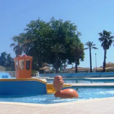 Photo camping Bosc d'En Roug : piscine avec bateau jouet et palmiers.