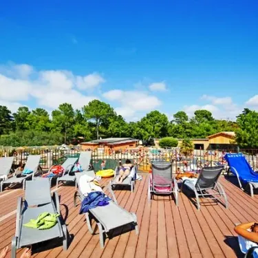 Camping Le Palace - terrasse en bois avec chaises longues et arbres en arrière-plan