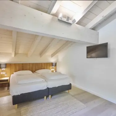 Chambre d'hotel penthouse avec sauna, 2 lits, plafond en bois, TV murale