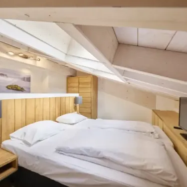Penthouse avec Sauna 4CH - 8P - Parc AlpChalets Portes du Soleil : lit double dans chambre avec toit en pente