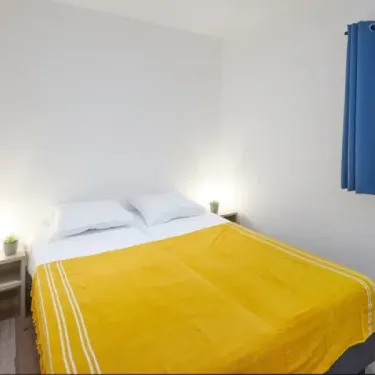 Chambre avec lit double et couvre-lit jaune dans l'accommodations Cigale 2CH - Village des Cigales