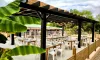 Terrasse du camping Le Pardaillan avec pergola, tables blanches et feuilles de bananier