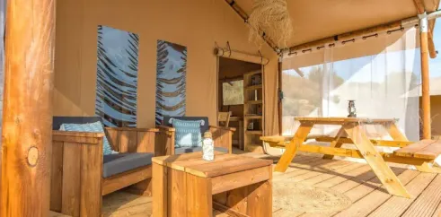 Intérieur du lodge avec canapé, table et table de pique-nique - Wood Lodge 2P, Camping Les Mizottes
