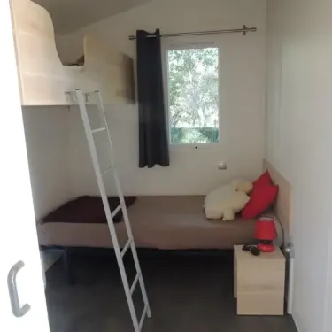 Mobil Home Confort+ Life PMR 2CH - 4P - Camping Domaine de Gajan, chambre avec lits superposés et fenêtre.