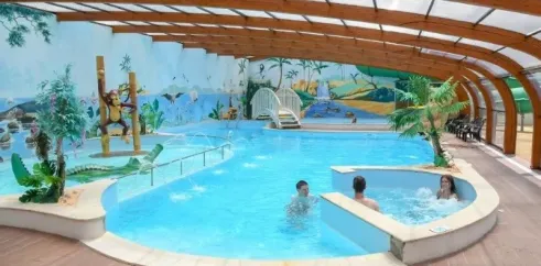 Piscine intérieure avec décor tropical et personnes nageant, Camping Paradis La Pomme de Pin