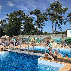 Piscine avec toboggan vert et enfants nageant, Camping Paradis La Pomme de Pin