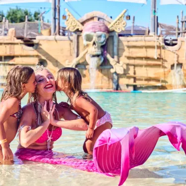 Mermaid dans la piscine entourée de deux enfants au Camping Les Sables d'Or Pirates World