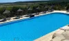 Piscine bleue avec chaises longues et parasols en paille au Camping Mer et Camargue
