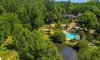 Vue aérienne du Camping Aqua Viva, avec piscine entourée de forêt et d'un cours d'eau adjacent.