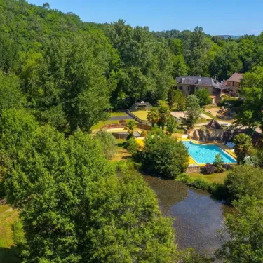 Vue aérienne du Camping Aqua Viva, avec piscine entourée de forêt et d'un cours d'eau adjacent.
