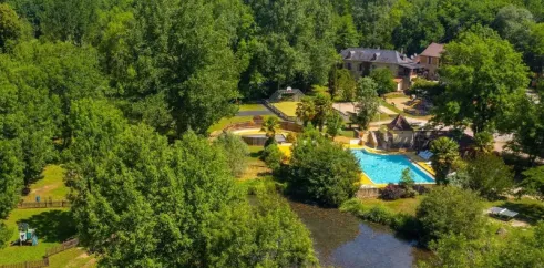 Vue aérienne du Camping Aqua Viva, avec piscine entourée de forêt et d'un cours d'eau adjacent.