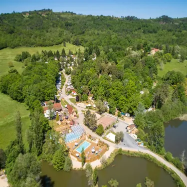 Vue aérienne du Camping Le Val d'Ussel entouré de forêt et d'un lac