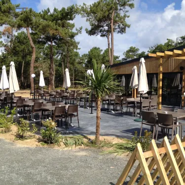 Camping Atlantique Club Montalivet : terrasse avec tables, chaises et parasols sous pins