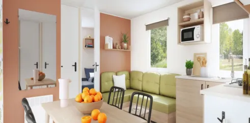 Mobil Home Aqua 3 Chambres 6/8 Personnes Clim TV - Domaine du Golfe de Saint-Tropez : salle à manger avec table et canapé vert