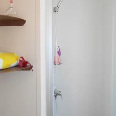 Détail de la douche avec étagères et articles de toilette