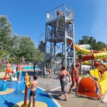 Enfants utilisent une grande structure aquatique à l'entrée d'un parc aquatique du Camping Jardins de l'Atlantique.