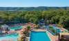 Vue aérienne du camping avec plusieurs piscines, chaises longues et forêt environnante.