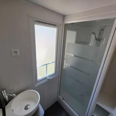 Salle de bain du Mobil Home, douche vitrée, lavabo rond, fenêtre