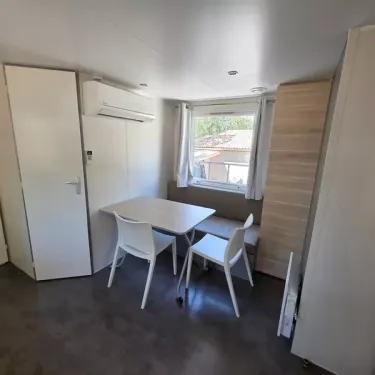 Salon du Mobil Home avec table, chaises, climatisation, armoire