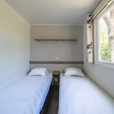 Mobil Home Aqua 2 Chambres 4 Personnes Terrasse semi-couverte Clim - Domaine de Chaussy : chambre avec deux lits et étagères