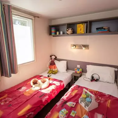Chambre d'enfant avec deux lits, jouets, étagères, rideaux