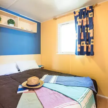 Chambre du Mobil Home Aqua 2 chambres à Le Mas de Sireuil, lit, couverture, chapeau