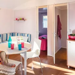 Mobil Home Aqua - salle à manger avec table et chaises, vue sur la chambre