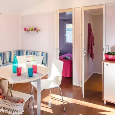 Mobil Home Aqua - salle à manger avec table et chaises, vue sur la chambre