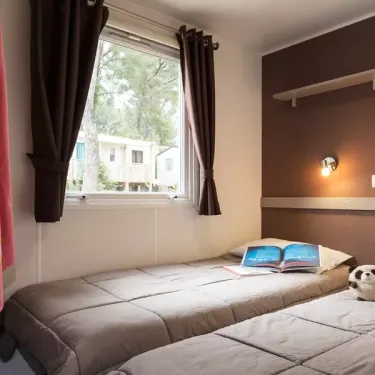 Mobil Home Aqua - chambre avec lits, fenêtre et rideaux