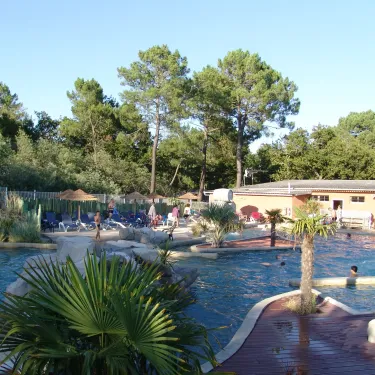Piscine entourée d'arbres et de chaises longues au Camping Le Palace