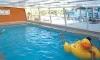 Enfant sur un flotteur canard dans une piscine couverte au Camping Les Salisses