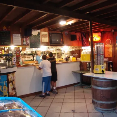 Photo camping Le Palace : bar sous toit en bois avec bouteilles