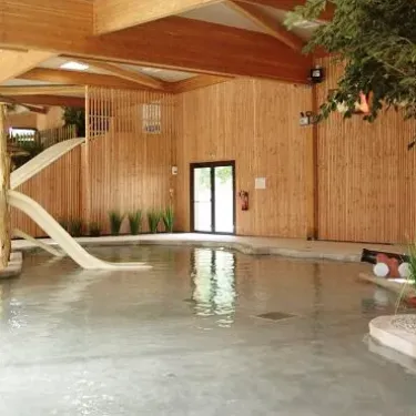 Piscine intérieure avec toboggan en bois au Camping Le Palace
