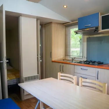 Mobil Home Aqua 2 chambres : cuisine avec table et chaises, vue sur chambre