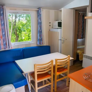 Mobil Home Aqua 2 chambres : coin repas avec canapé bleu et table