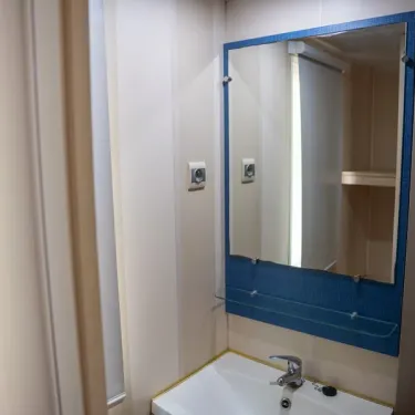 Salle de bain du Mobil Home Aqua avec lavabo, miroir et étagères