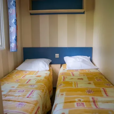 Chambre avec deux lits, tête de lit bleue et rideaux colorés