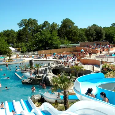 Piscine avec toboggan bleu et palmiers au Camping Le Palace