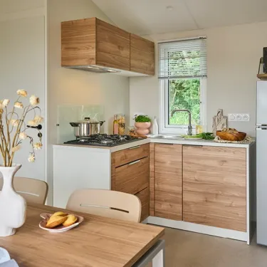 Cuisine du mobil home avec plancha, placard en bois et table à manger