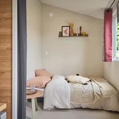 Chambre avec lit simple, couverture, table ronde et étagère murale