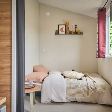 Chambre avec lit simple, couverture, table ronde et étagère murale